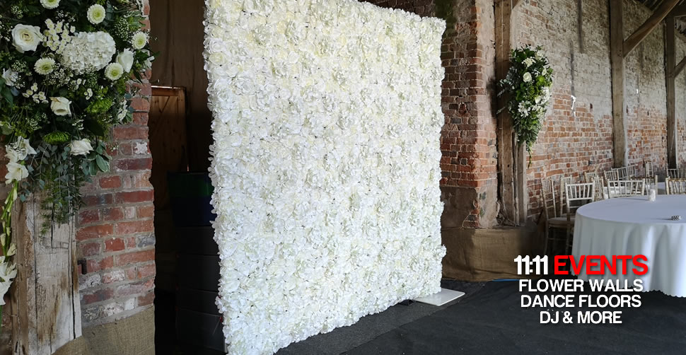 White Flower Wall backdrop covering up storage area in rustic barn wedding, Dorset